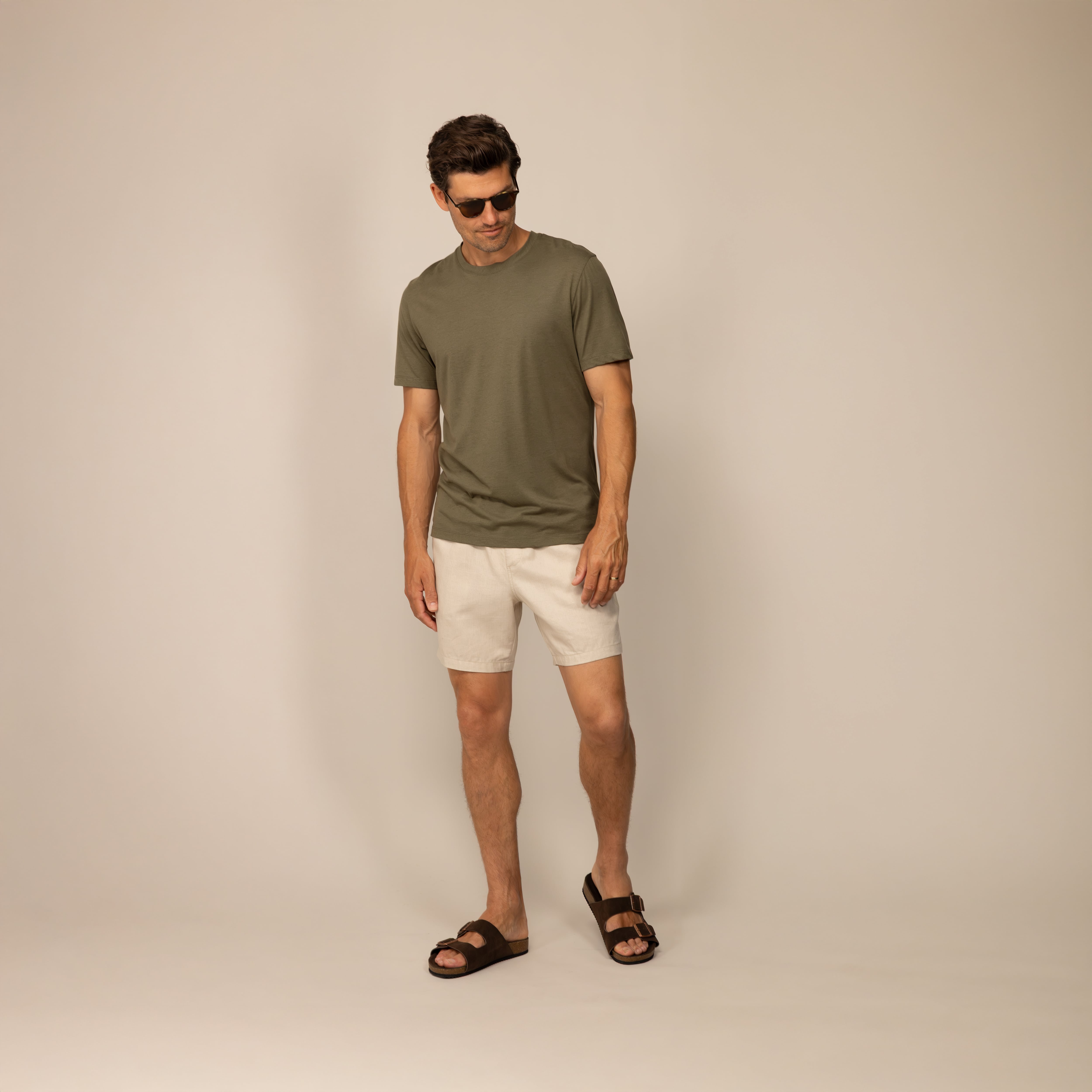 Man wearing casual linen blend shorts in natural sand, front view.