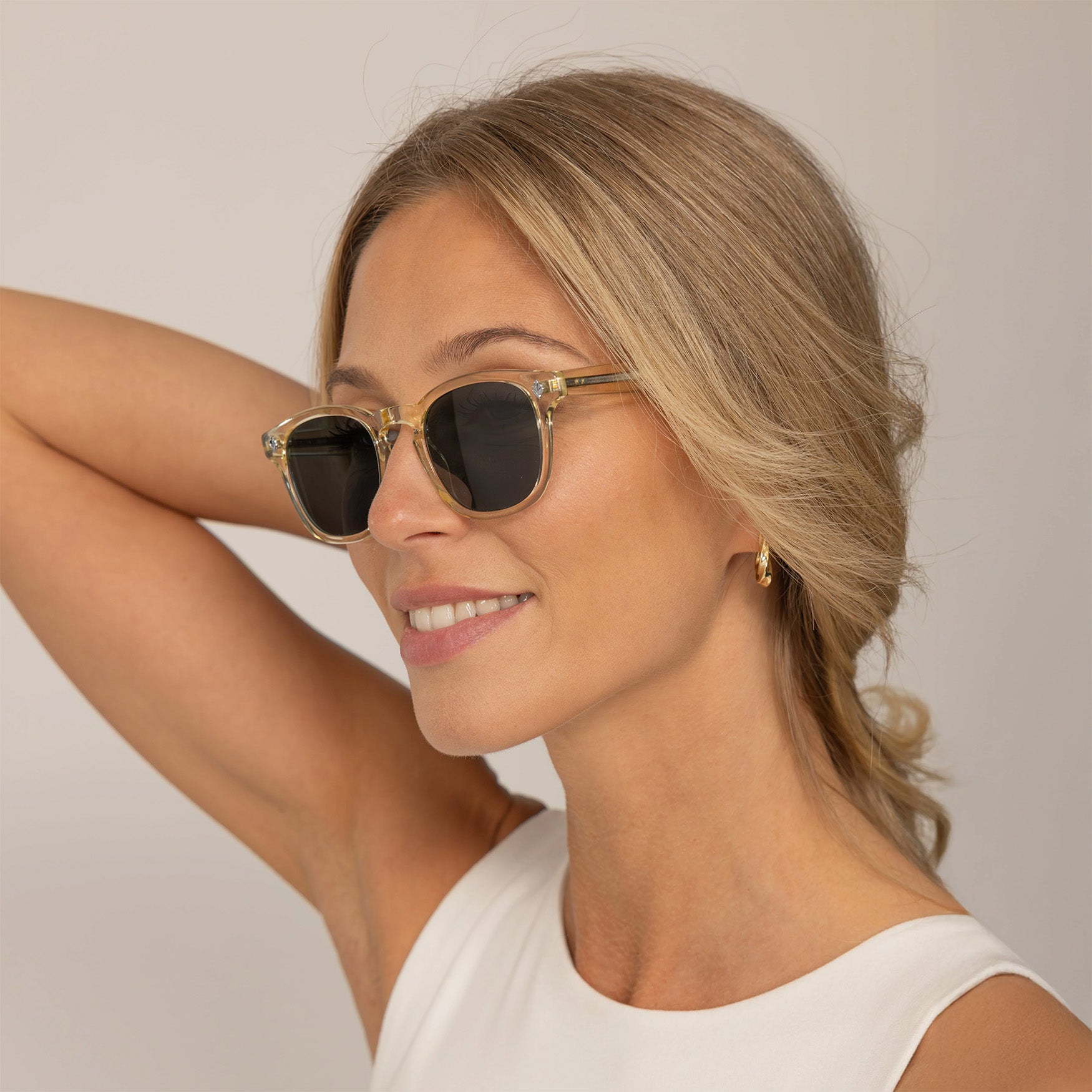 Woman wearing Garrett Leight Ace Sun Sunglasses in Pure Glass, front view.