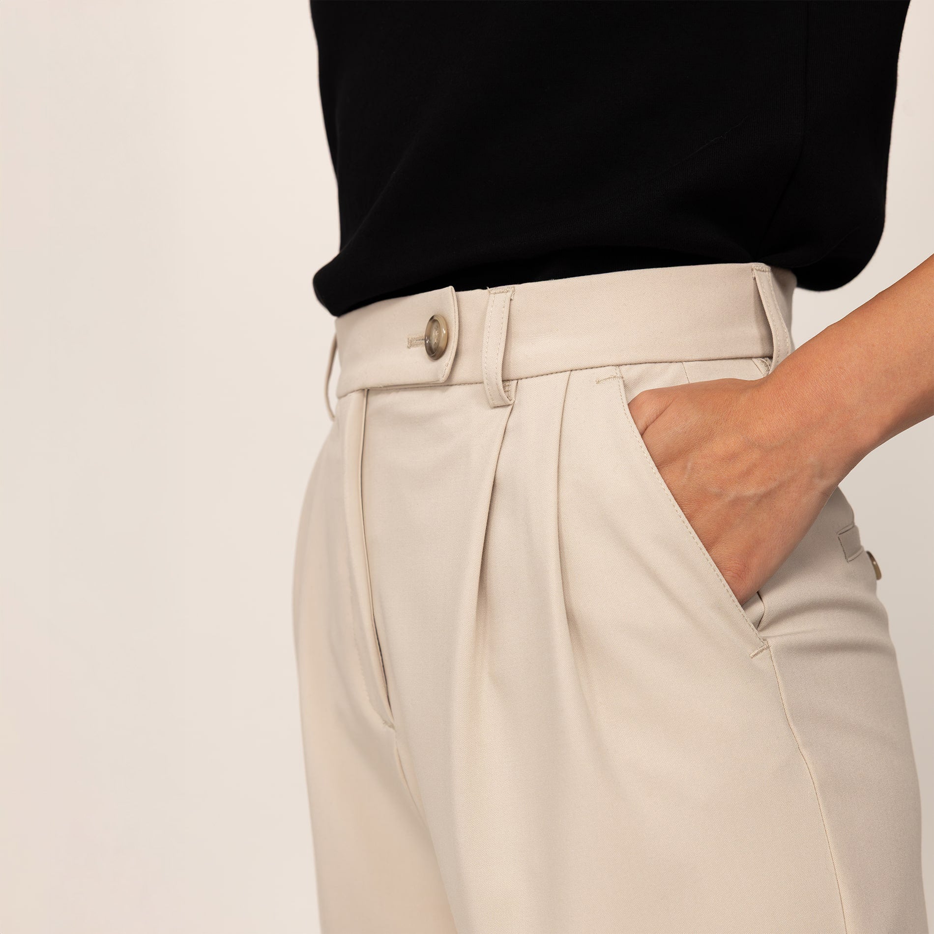 Woman wearing High-Waisted Tapered Trousers in Stone, closeup.
