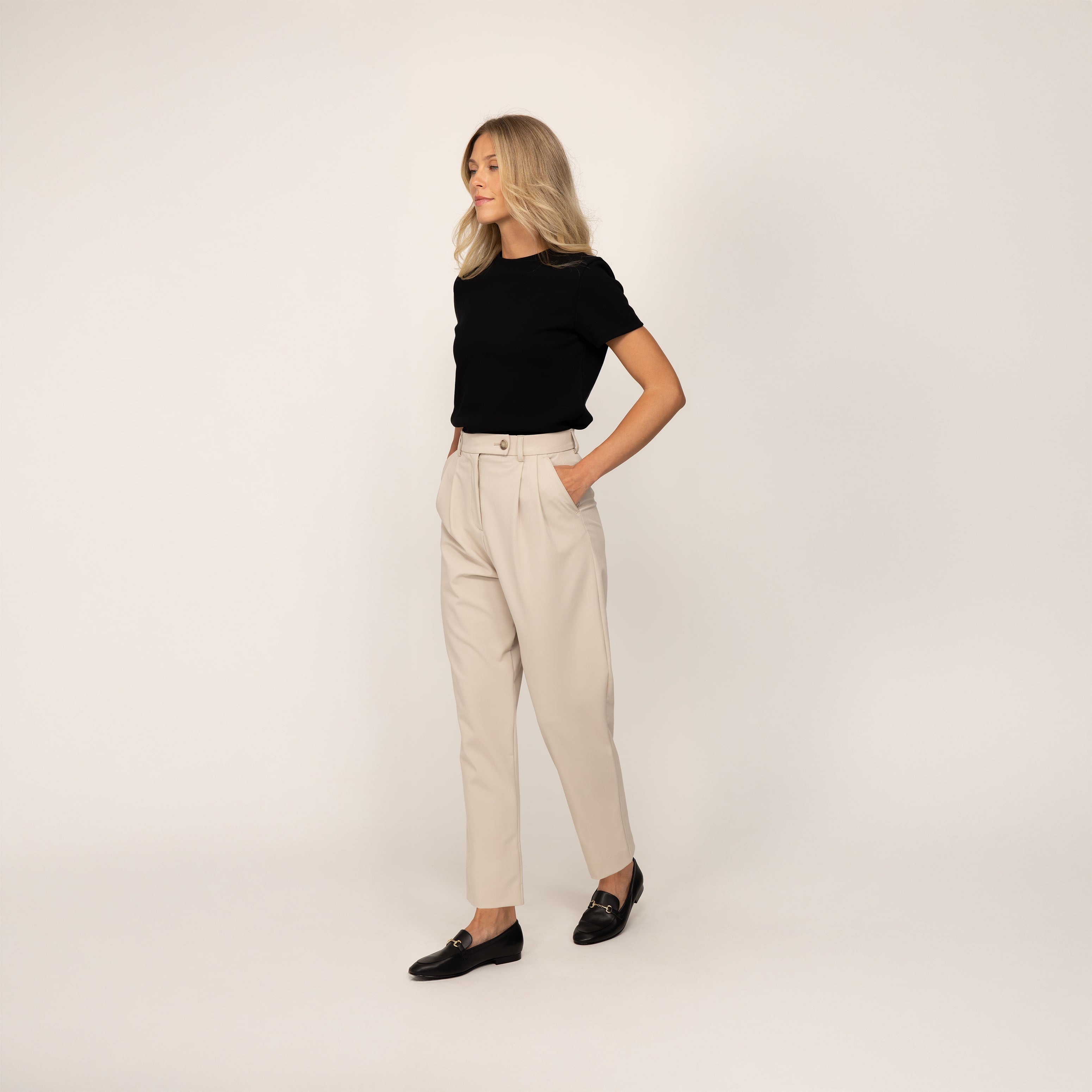 Woman wearing Marame High-Waisted Tapered Trousers in Stone, full view.