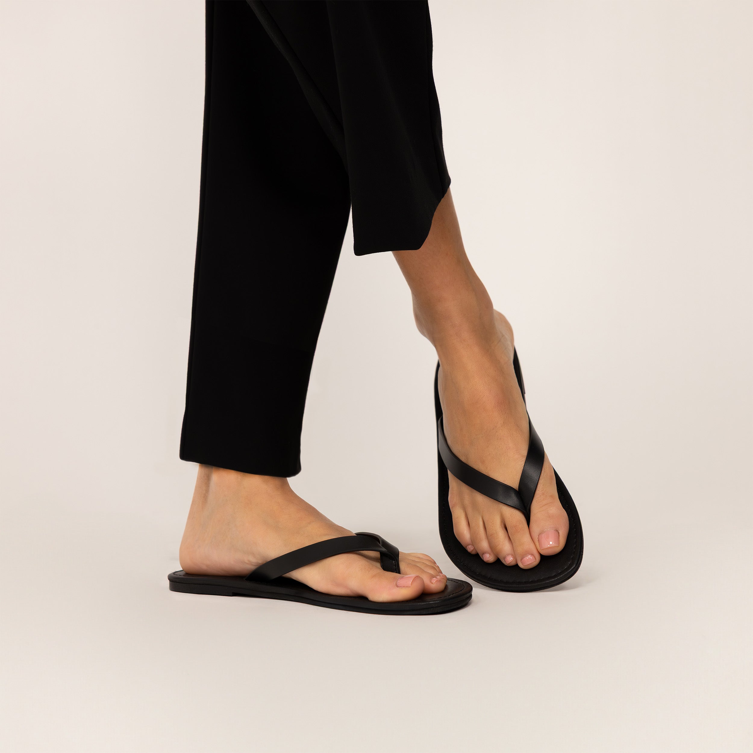 Woman wearing Marame Leather Flip Flops in Black, front view.