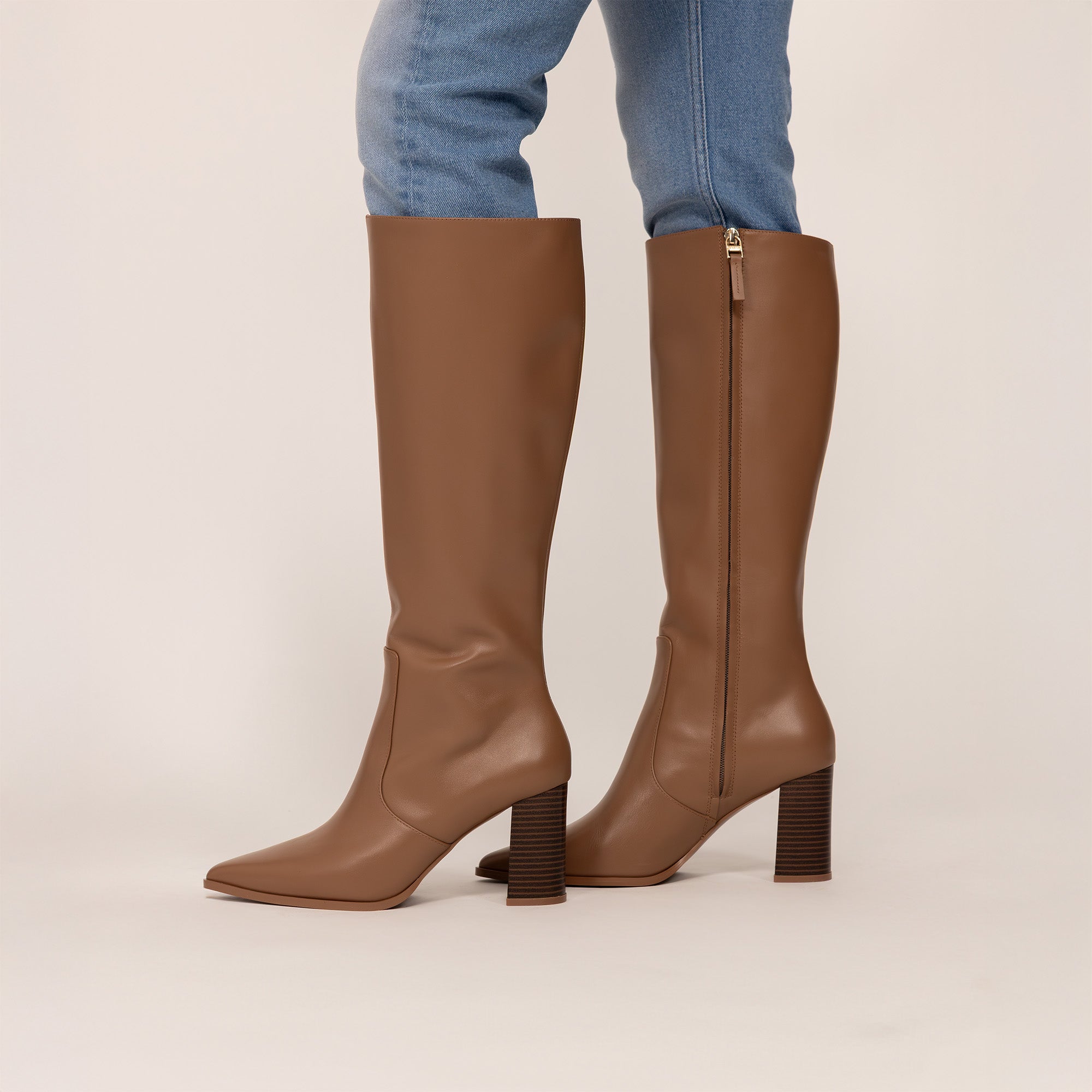 Woman wearing Marame Leather Knee-High Boots in Brown, side view.