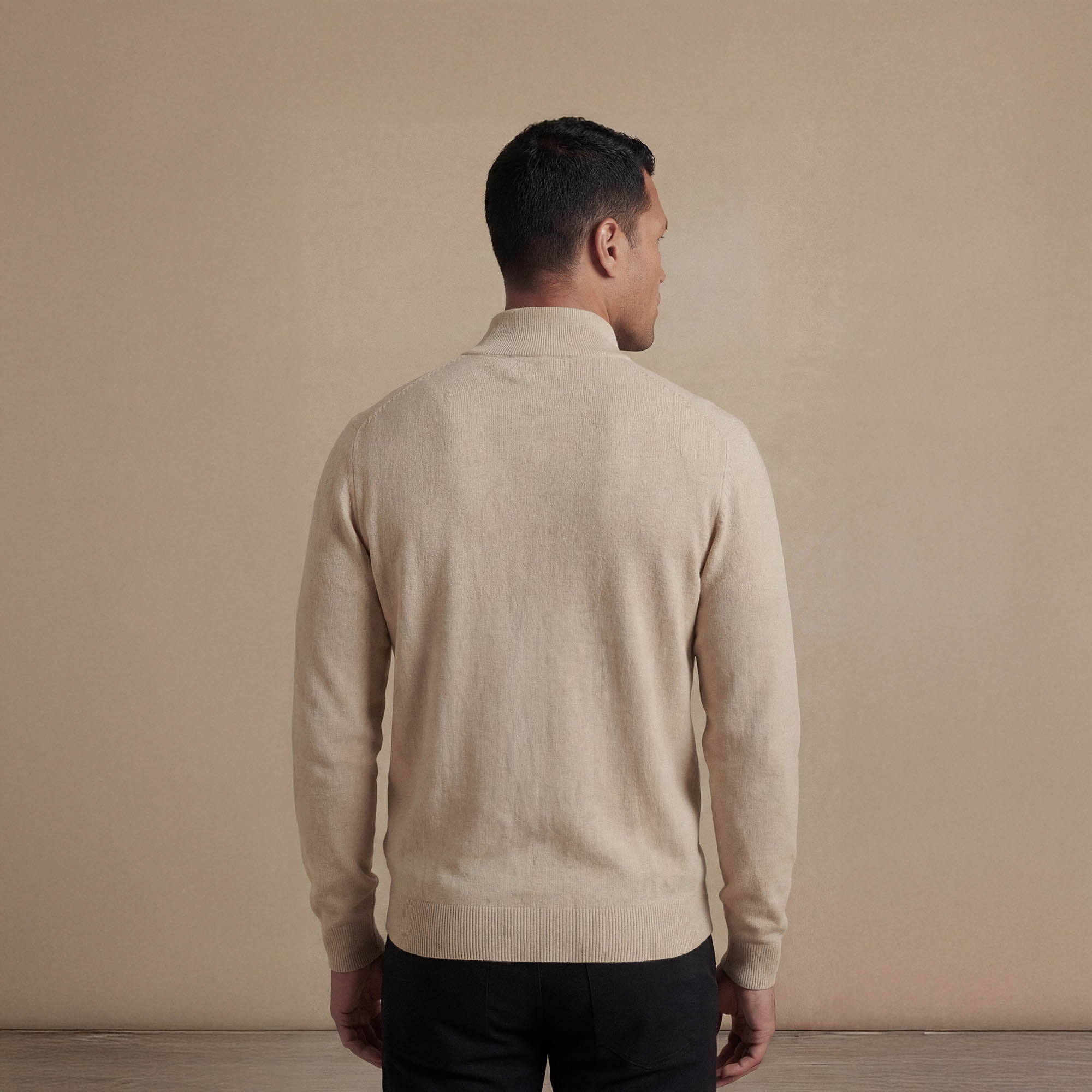 Man wearing a navy half zip jumper, back view. |beige pearl