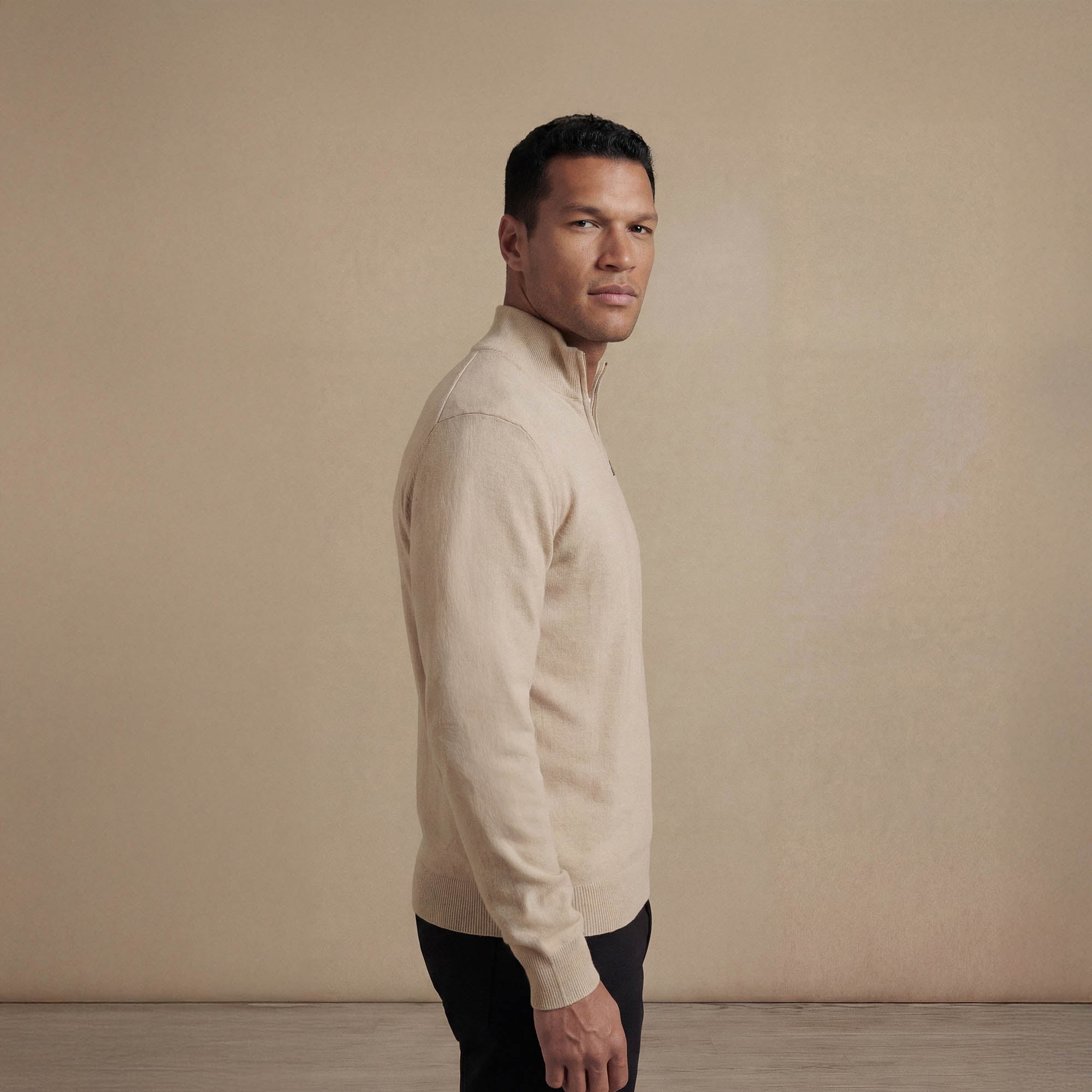 Man wearing a navy half zip jumper, side view. |beige pearl