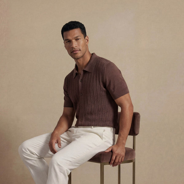 Man wearing Marame cable knit shirt in conker brown, seated view. |conker brown