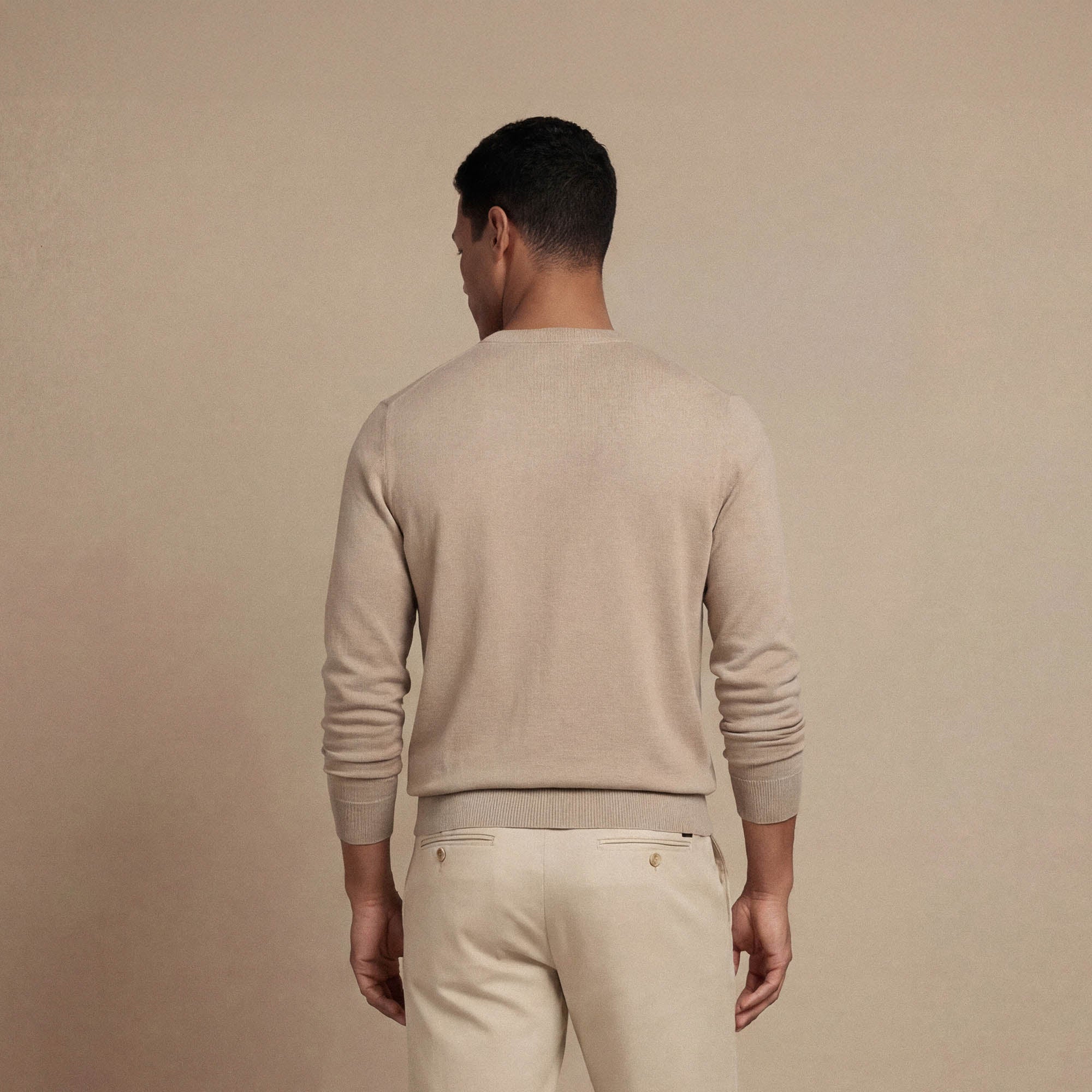 Man wearing a Marame Fine Knit Crew Neck Jumper in putty dove back view. |putty dove