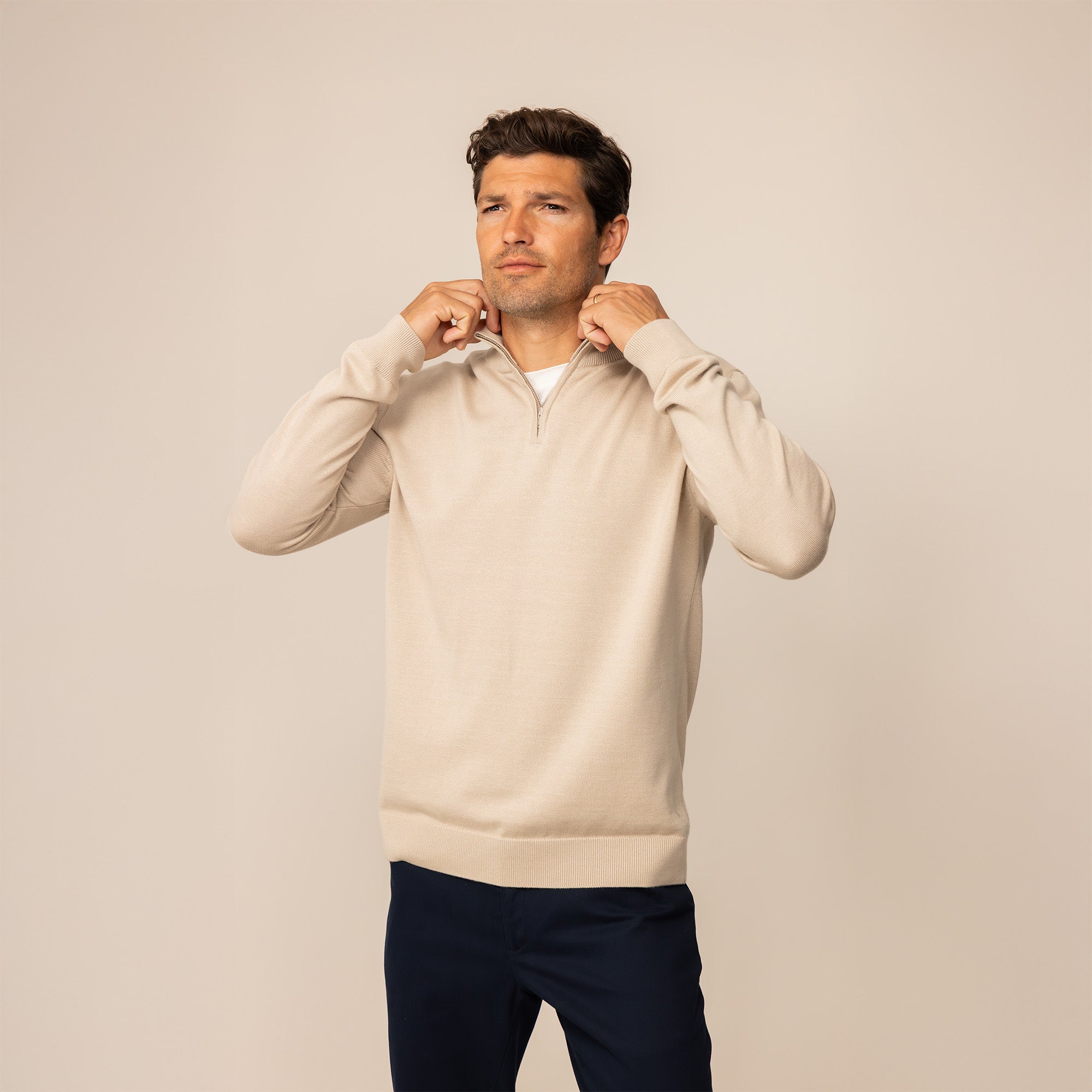 Man wearing a beige pearl half zip jumper, front view.