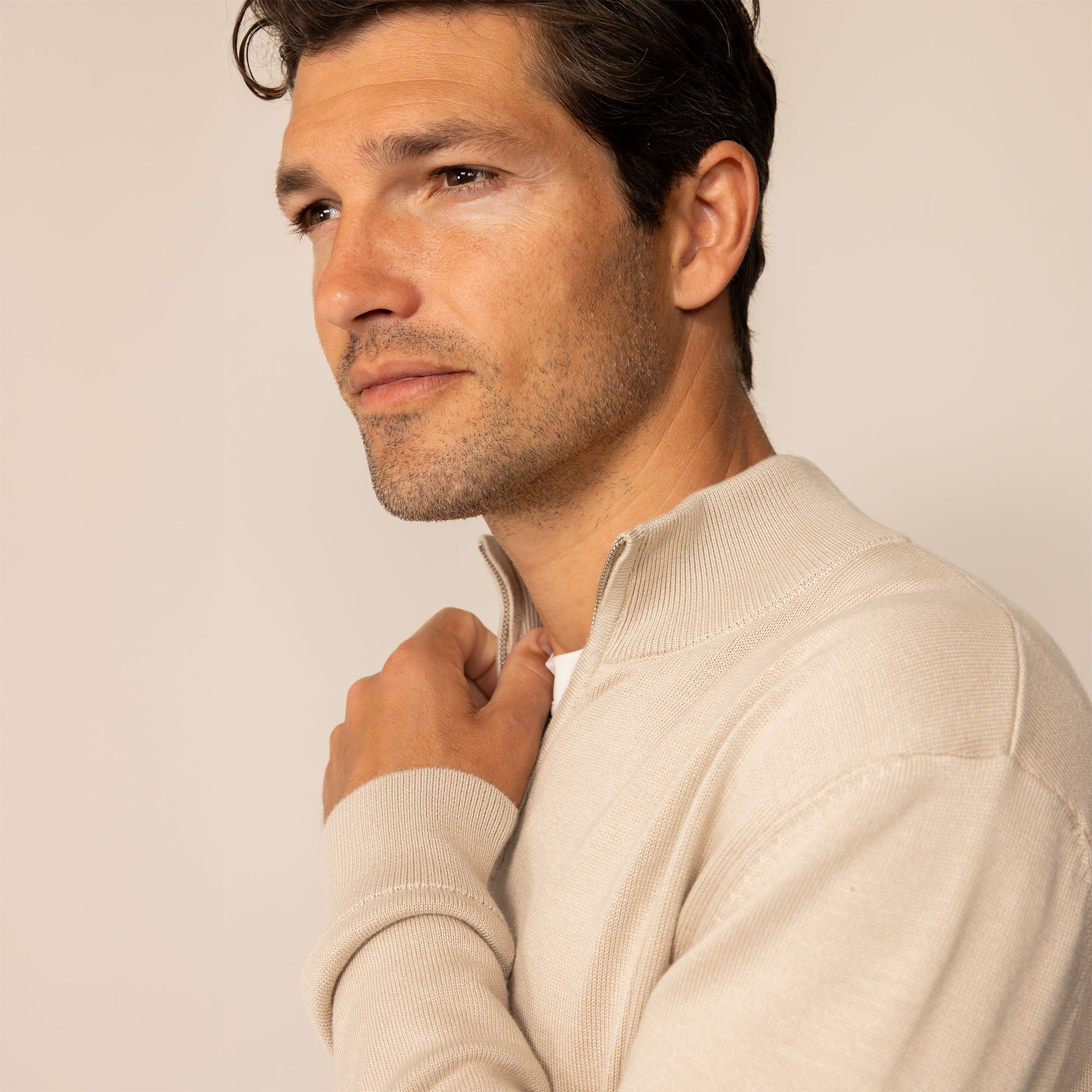 Man wearing a beige pearl half zip jumper, closeup.