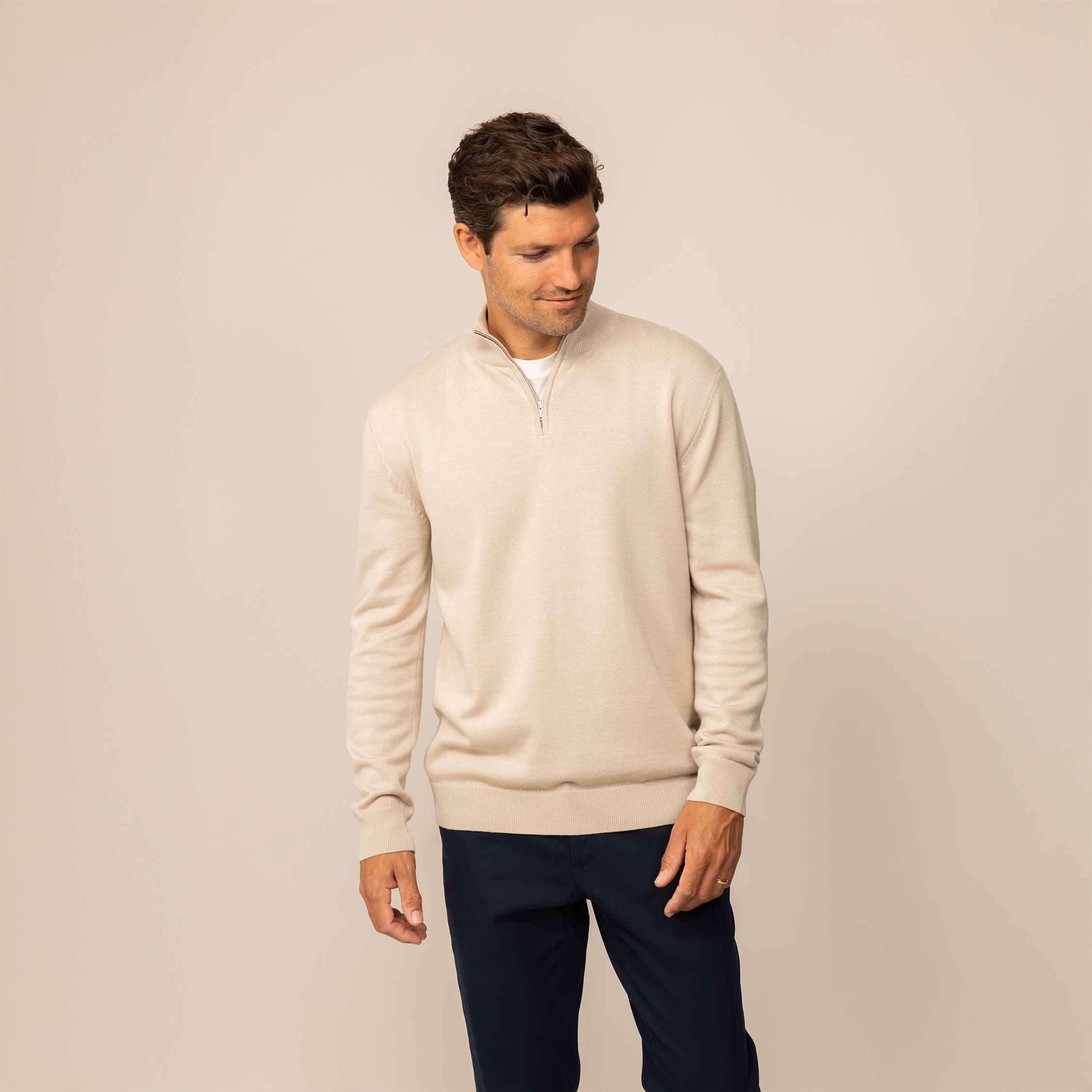 Man wearing a beige pearl half zip jumper, front view.