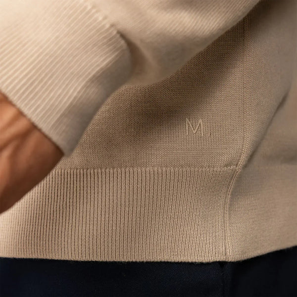 Man wearing a beige pearl half zip jumper, closeup.