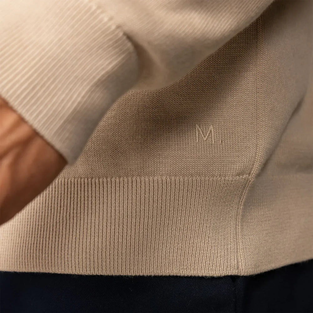 Man wearing a beige pearl half zip jumper, closeup.
