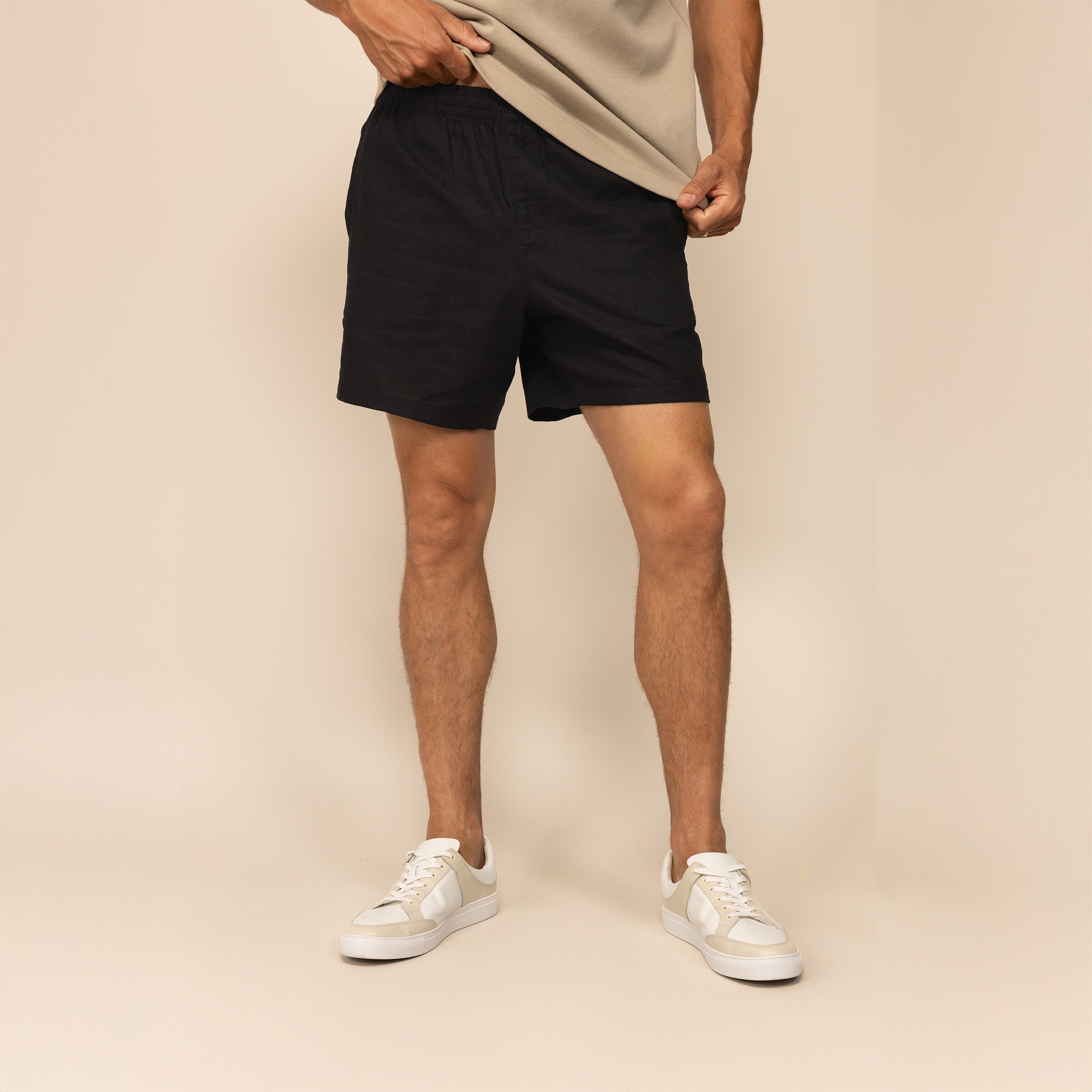 Man wearing black casual linen blend shorts, front view.