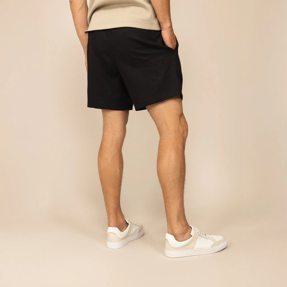 Man wearing black casual linen blend shorts, rear view. |black