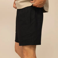 Man wearing black casual linen blend shorts, side view. |black