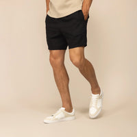 Man wearing black casual linen blend shorts, front view.