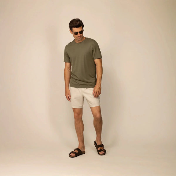 Man wearing casual linen blend shorts in natural sand, full shot.