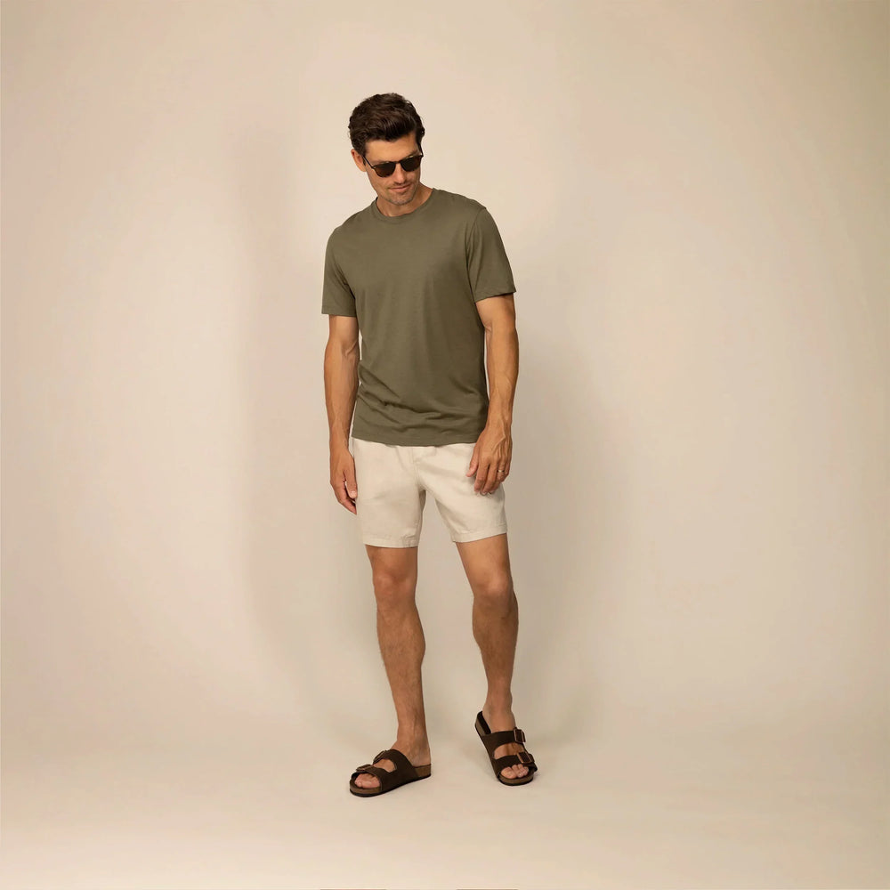 Man wearing casual linen blend shorts in natural sand, full shot.