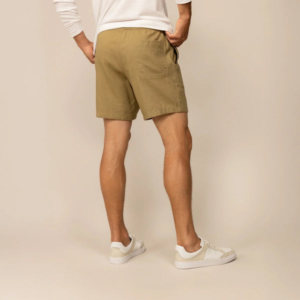 Man wearing casual linen blend shorts in natural sand, rear view. |barley green