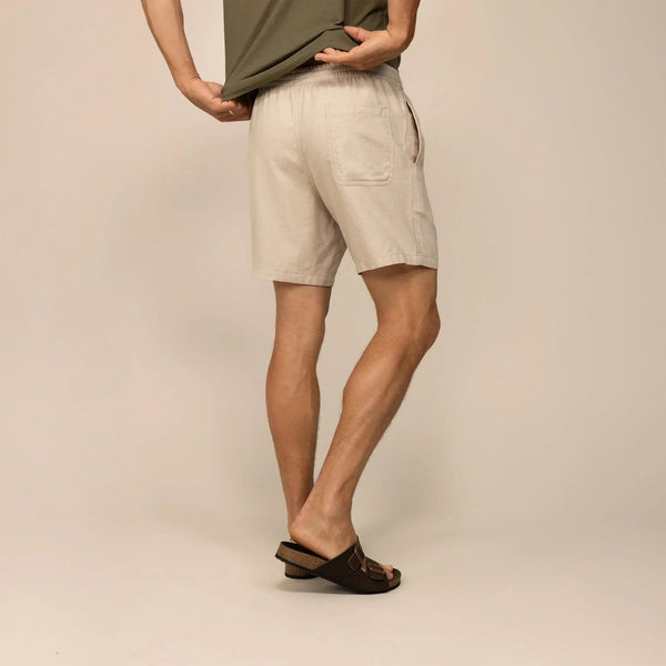 Man wearing casual linen blend shorts in natural sand, rear view.