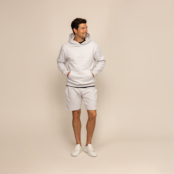 Man wearing a Marame cotton fleece hoodie in Ash White, full view.