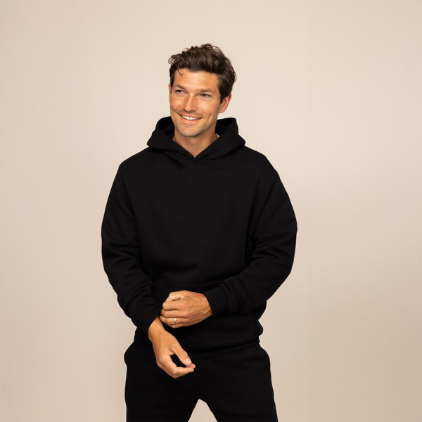 Man wearing a cotton fleece hoodie in Black, front view.