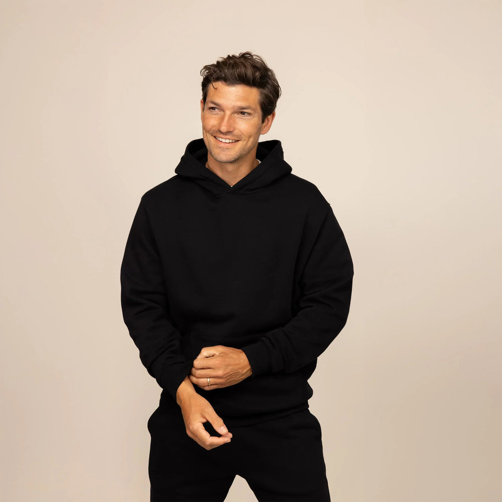 Man wearing a cotton fleece hoodie in Black, front view.