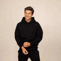 Man wearing a cotton fleece hoodie in Black, front view.
