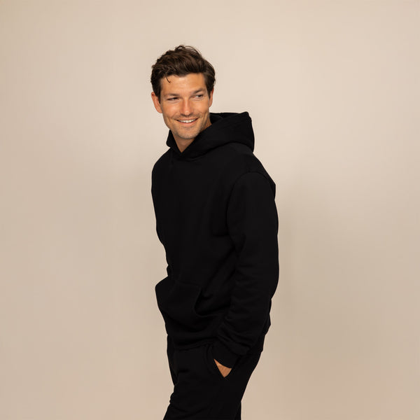 Man wearing a Marame cotton fleece hoodie in Black, front view.