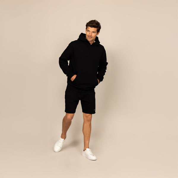 Man wearing a Marame cotton fleece hoodie in Black, full view.