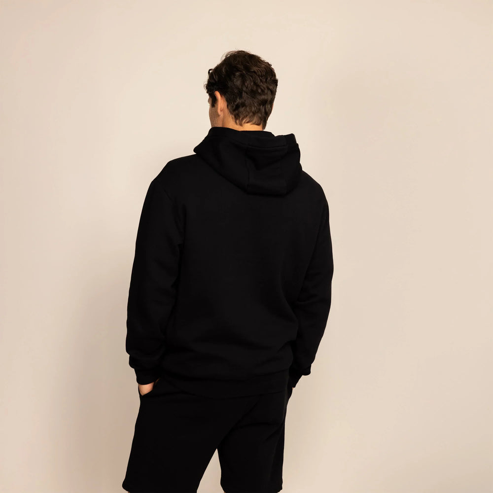 Man wearing a Marame cotton fleece hoodie in Black, rear view.