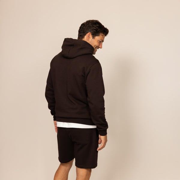 Man wearing a cotton fleece hoodie in Smoked Brown, rear view.