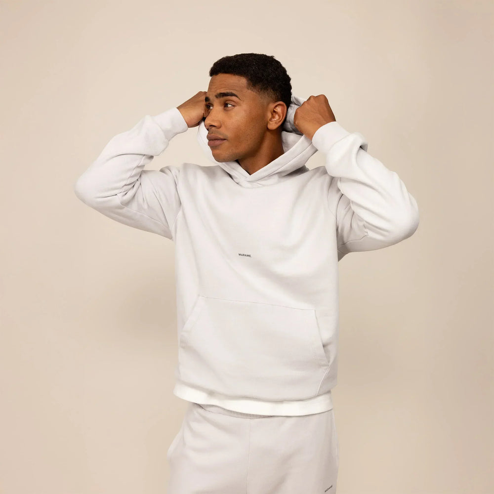 Man wearing a Marame cotton fleece Logo Hoodie in Ash White, front view.