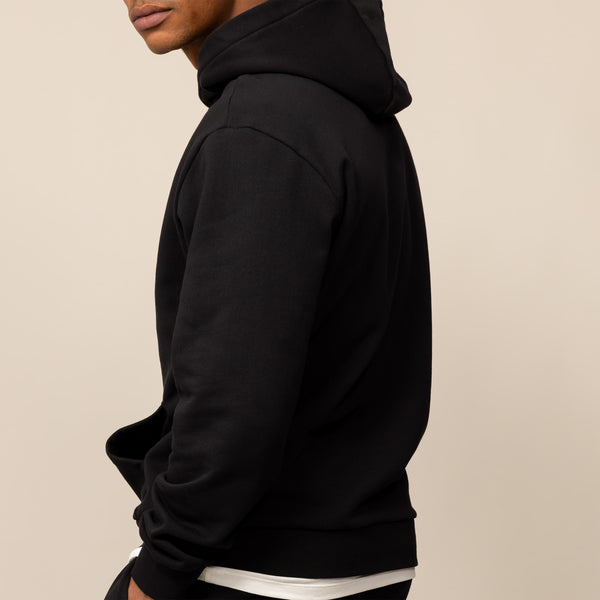 Man wearing a Marame Cotton Fleece Logo Hoodie in Black, closeup.
