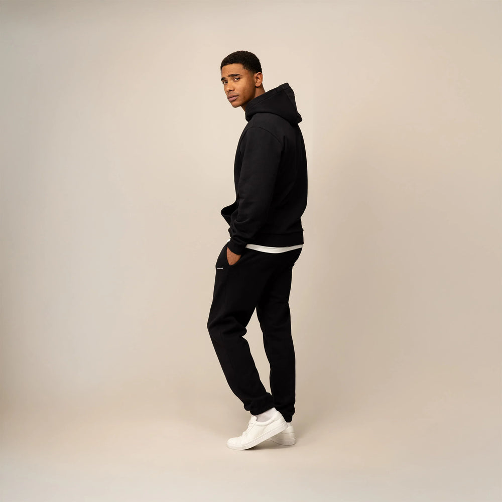 Man wearing a Cotton Fleece Logo Hoodie in Black, side view.