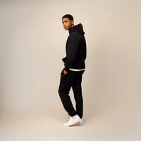 Man wearing a Cotton Fleece Logo Hoodie in Black, side view.