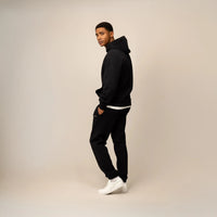 Man wearing a Cotton Fleece Logo Hoodie in Black, side view.|black