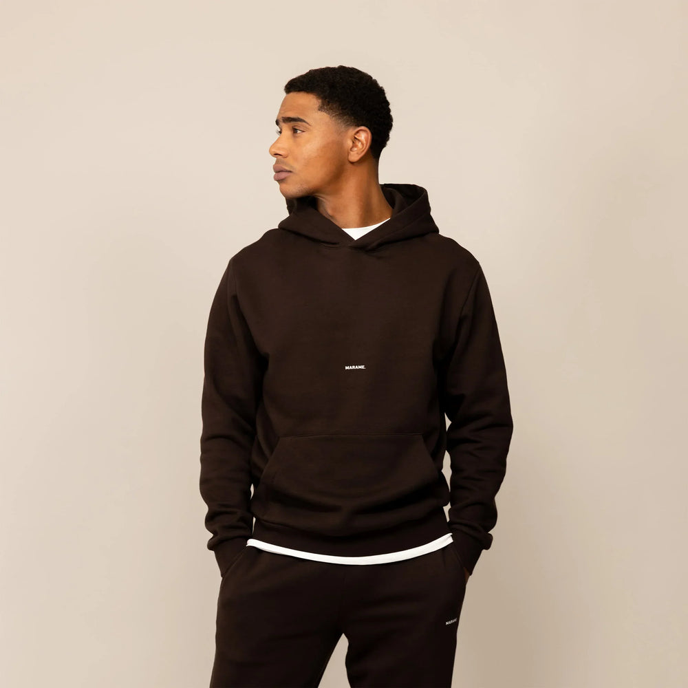 Man wearing a Marame cotton fleece Logo Hoodie in Smoked Brown, front view.