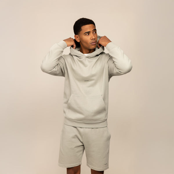 Man wearing a Marame cotton fleece Logo Hoodie in Wolf Grey, front view.