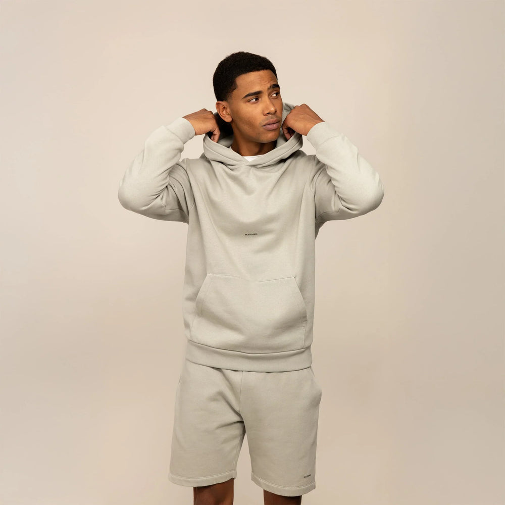 Man wearing a Marame cotton fleece Logo Hoodie in Wolf Grey, front view.