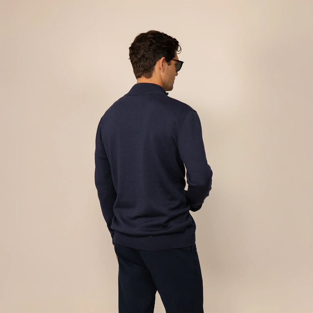 Man wearing a navy half zip jumper, back view.