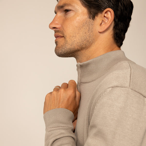 Man wearing a putty dove half zip jumper, side view.