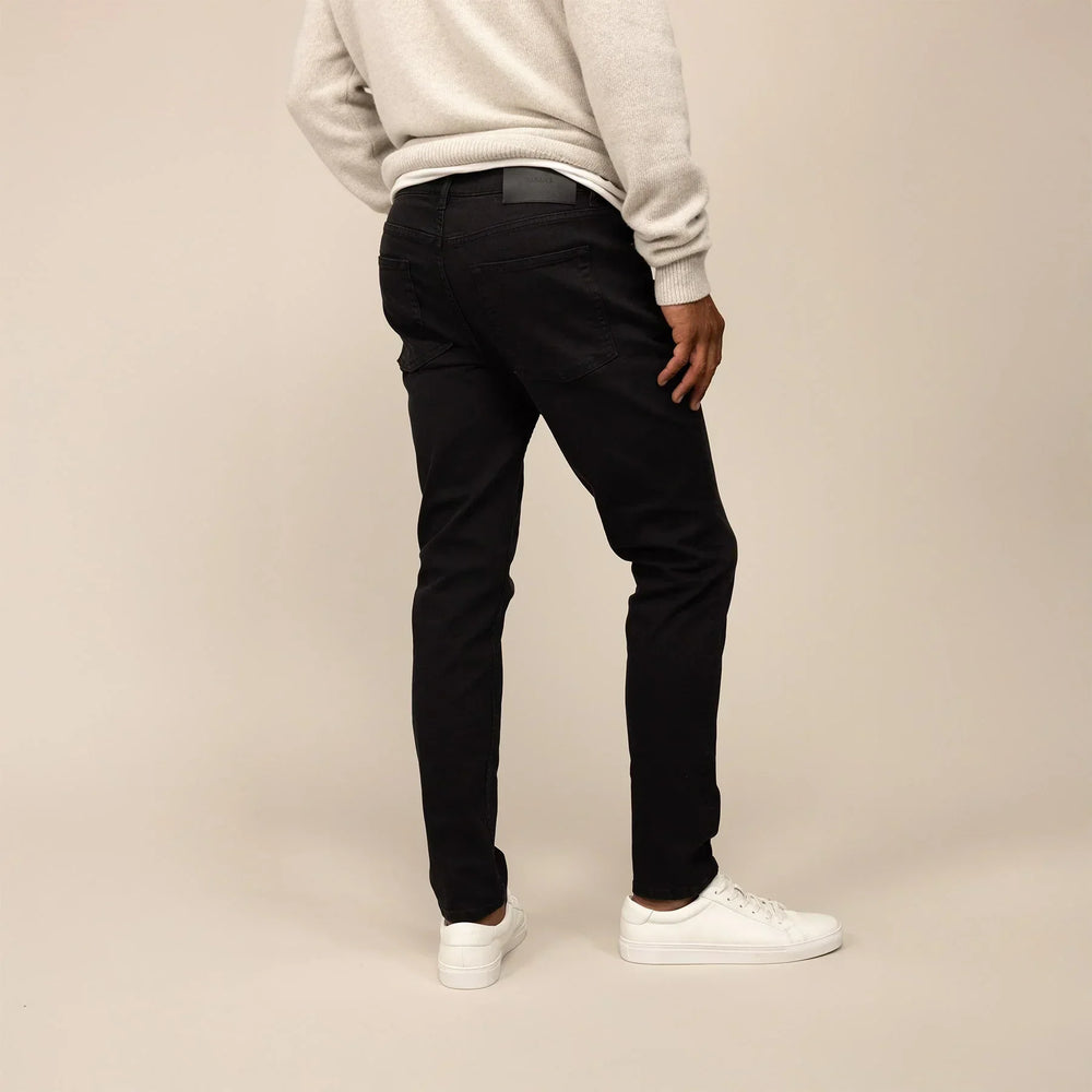 Man wearing Slim Leg Denim Jeans in Black, rear view.
