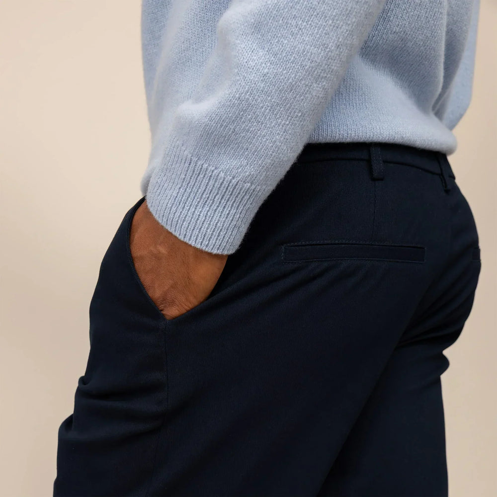 Man wearing Marame Tapered Chinos in Navy, rear view.