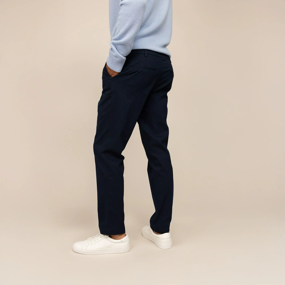 Man wearing Marame Tapered Chinos in Navy, rear view.