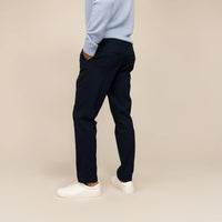 Man wearing Marame Tapered Chinos in Navy, rear view.