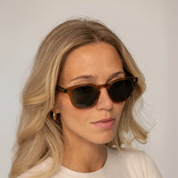 Womean wearing Garrett Leight Ace Sun Sunglasses in Caramel, front view.