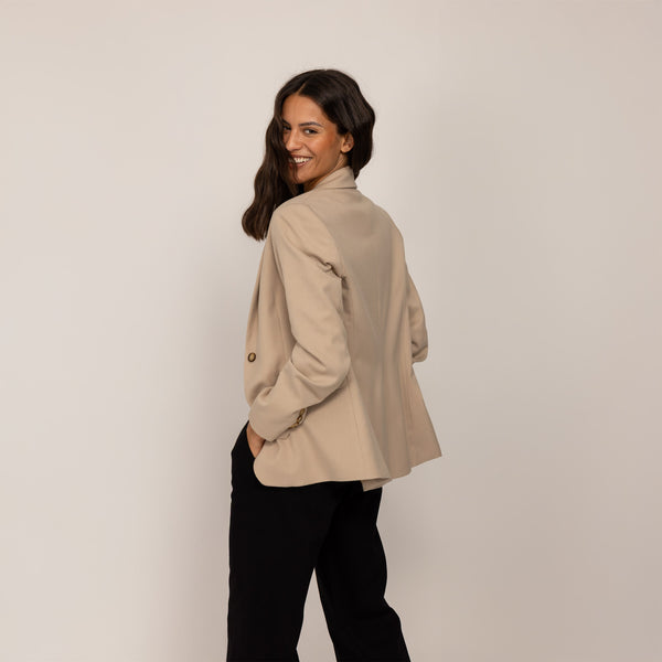 Woman wearing a Marame Classic Blazer in Natural Beige, rear view.