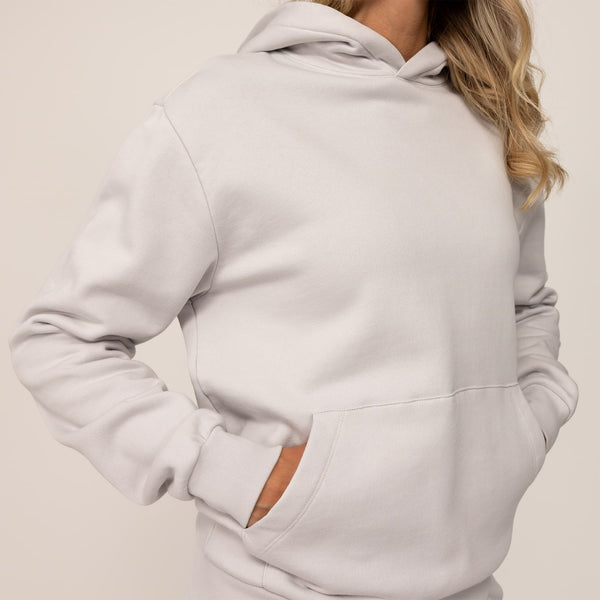 Woman wearing cotton fleece hoodie in Ash White, closeup.