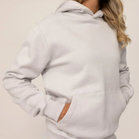 Woman wearing cotton fleece hoodie in Ash White, closeup.