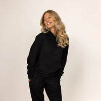 Woman wearing Marame cotton fleece hoodie in Black, front view.